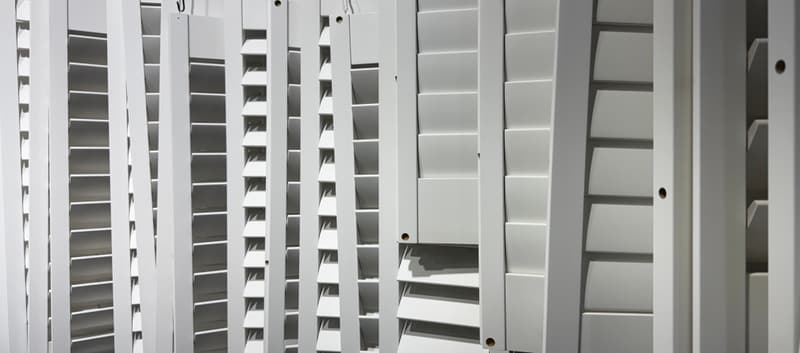 Painted shutter panels hanging side by side after finishing, louvres open