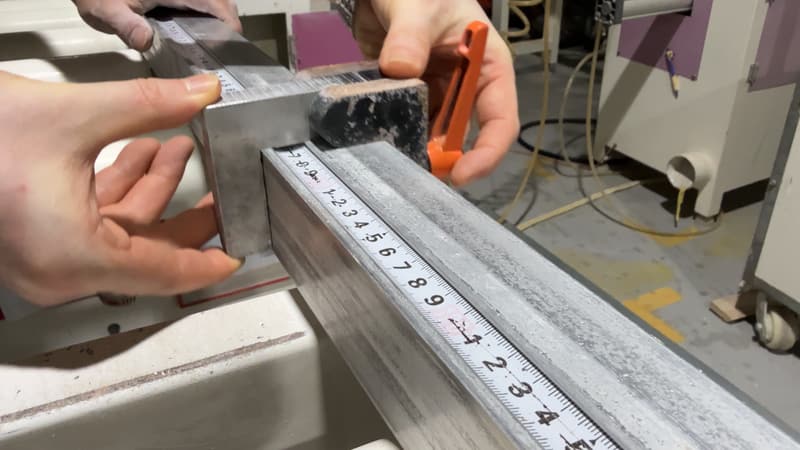 Hands setting a length stop against a measuring rule before a cut