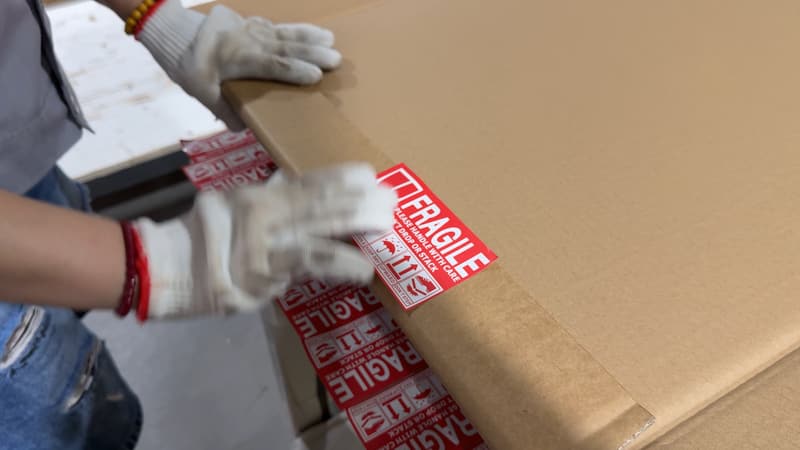 A shutter carton being taped and labelled fragile for shipping